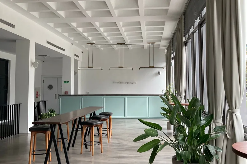 Empty open commercial space with a long table, stools and a plant
